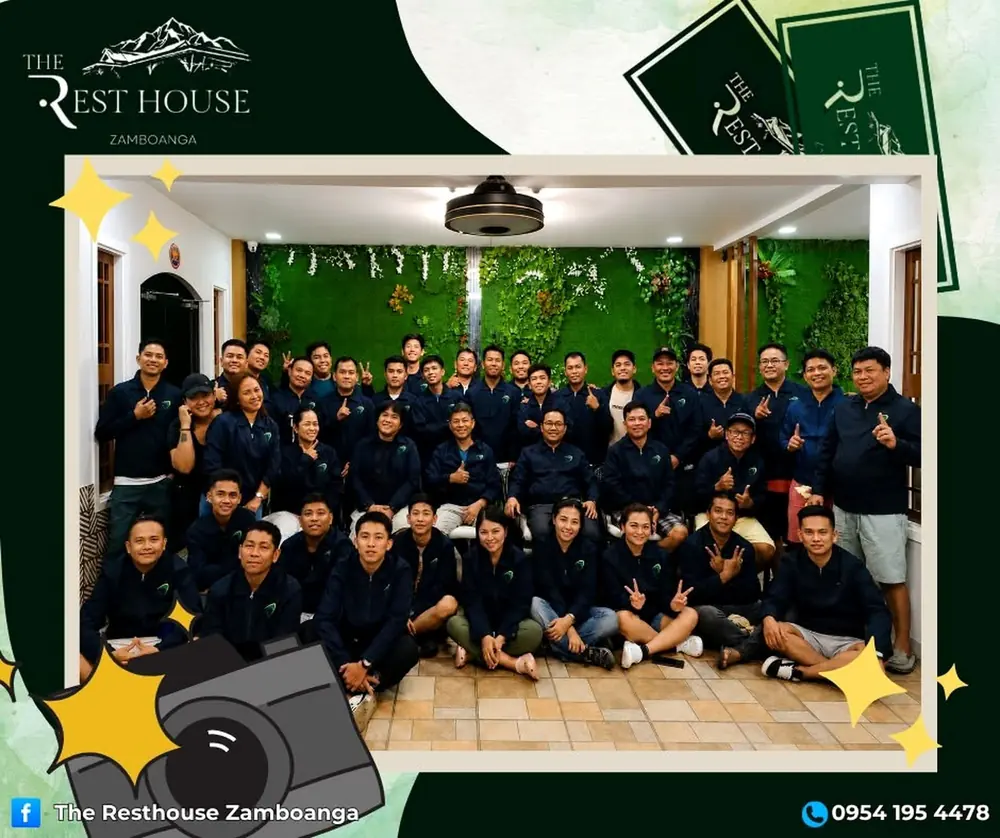 A large team in matching navy jackets posing together in the common area