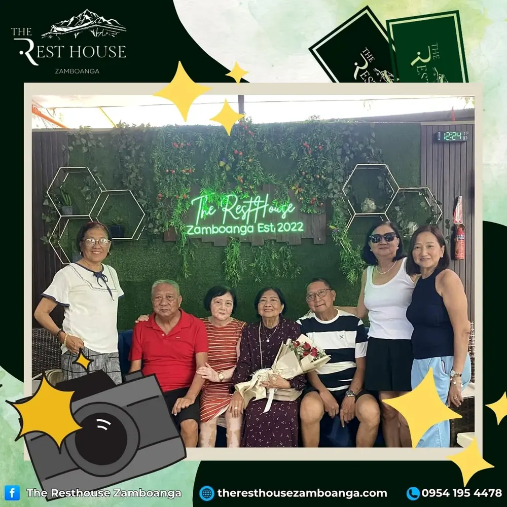 Seven friends and relatives posing under the resort's green neon sign, one holding a bouquet